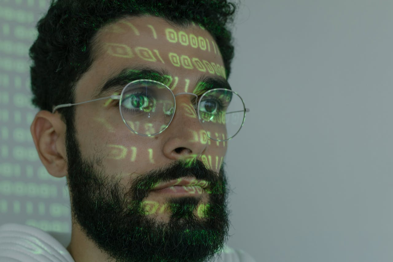 A bearded man with digital binary code projected on his face, symbolizing cybersecurity and technology.