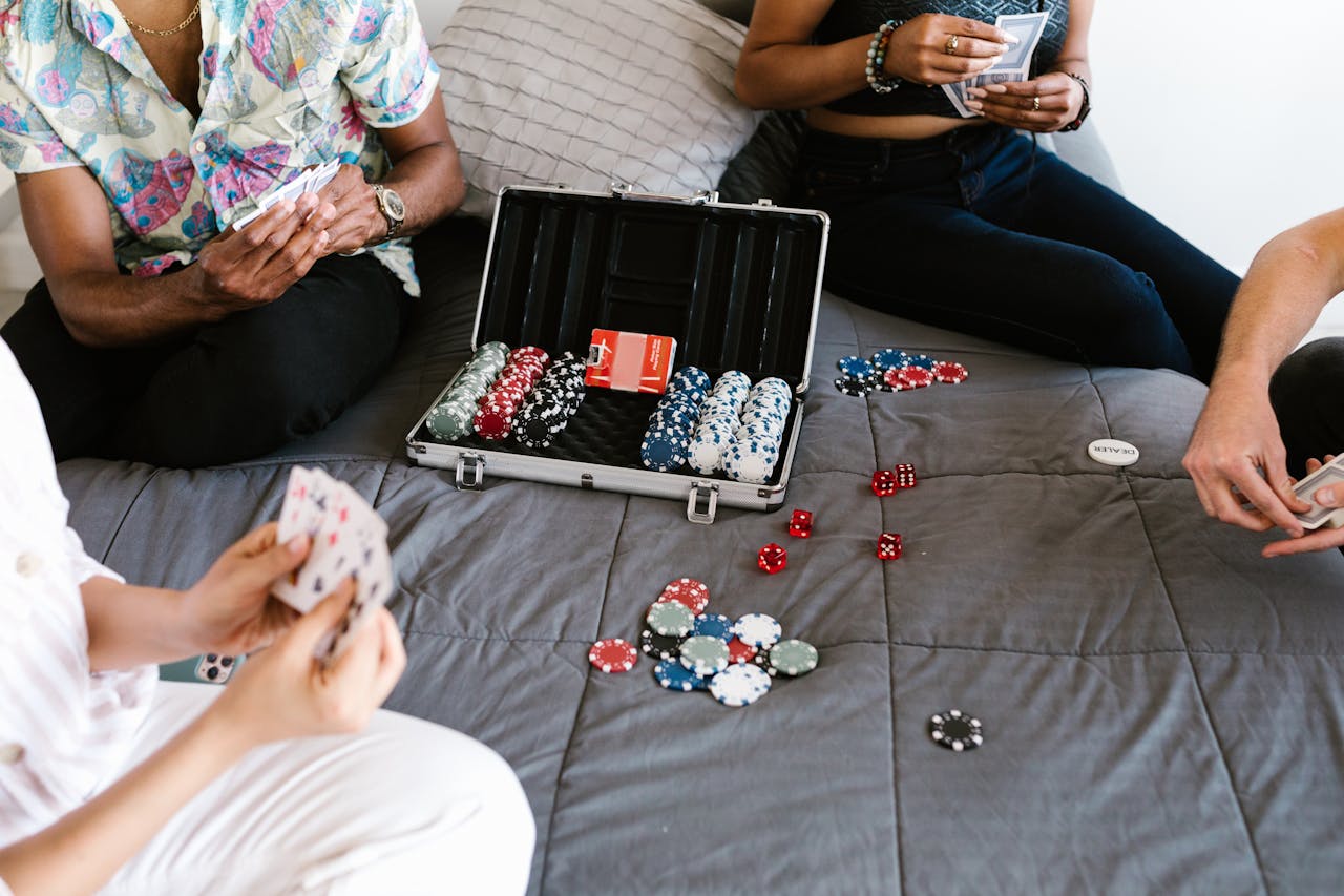 A group of adults playing poker with chips on a cozy bed setting, emphasizing friendship and leisure.