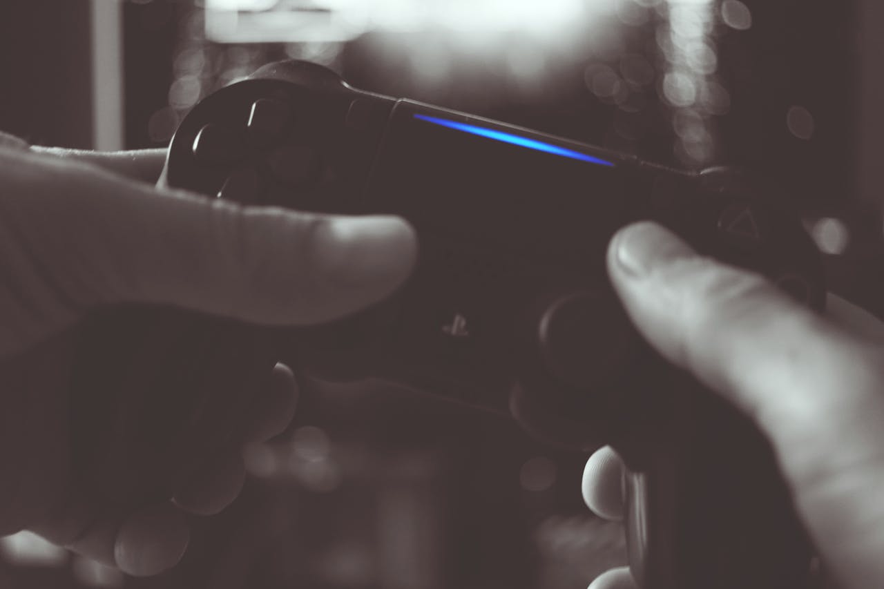 Close-up of hands gripping a gaming controller in dim light, emphasizing electronic entertainment.